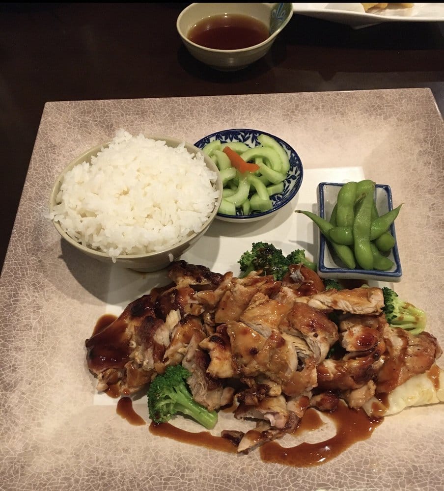 Teriyaki chicken with rice, cucumber salad, and edamame on a patterned plate