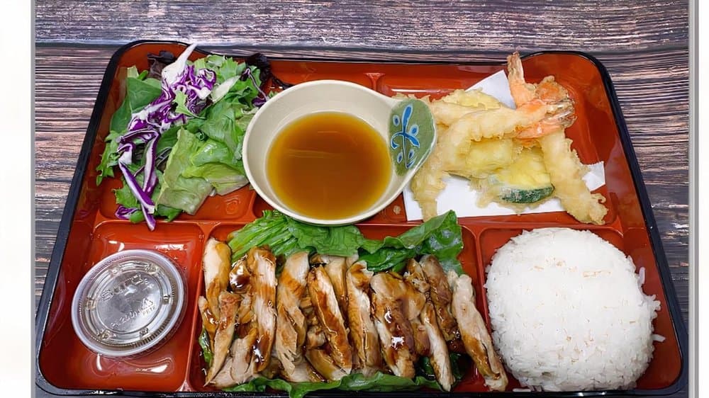 A bento box with teriyaki chicken, tempura, salad and rice