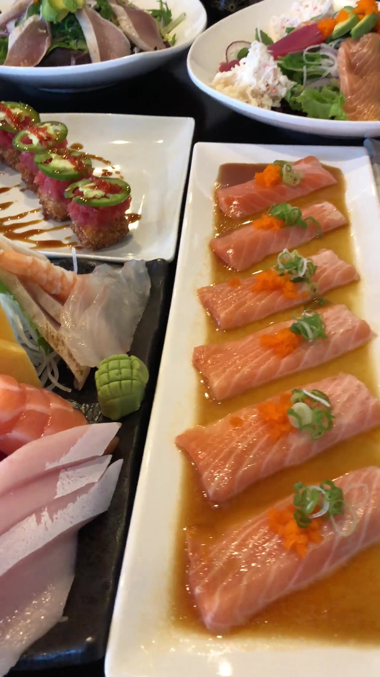 Sashimi, rolls and salmon carpaccio on the table